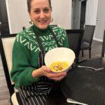 women in green sweater holding bowl of food inside