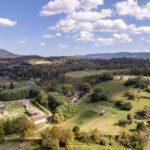 Scenic view of landscape with blue sky and few clouds along with end of summer trees and farm fields
